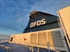 DFDS logo oplyst af solen der er på vej mod horisonten.